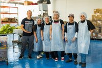 Group of employees wearing chef aprons and hair nets.