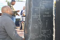 Man inspects a stone marker engraved with a map of the Bronx at an event celebrating the Bronx Greenway