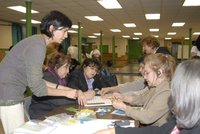Workshop attendees around a table placing game pieces on a board