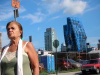 Woman wearing a white scarf looks off into the distance with vacant SPURA site and tall glass towers rising in the background