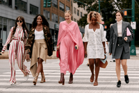 Five female models wearing fashionable outfits cross a street in Manhattan