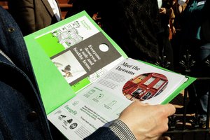 Shot of a green folder open with someone looking at the 1-pagers in the folder.