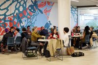 People in groups sitting in front of an indoor mural.