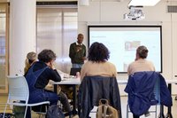 Someone presenting on Newsletters to a group of people at a table.