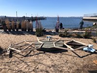 The frame of a Blue City Blue Block test garden sits on the beach with potted plants in the background waiting to be installed