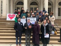 Group of advocates holding signs at a press conference on the steps of City Hall