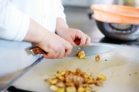 Food production worker cuts up fresh ginger