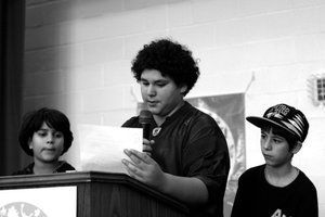 A young person gives remarks at the podium at Verde Summit while two others stand on either side of him
