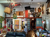 A man being interviewed in a large studio space, points to one of the many pieces of art decorating the room.