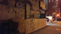 A closed off subway entrance covered by sheets of plywood