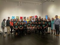 Large group photo inside a gallery space with artwork on the walls